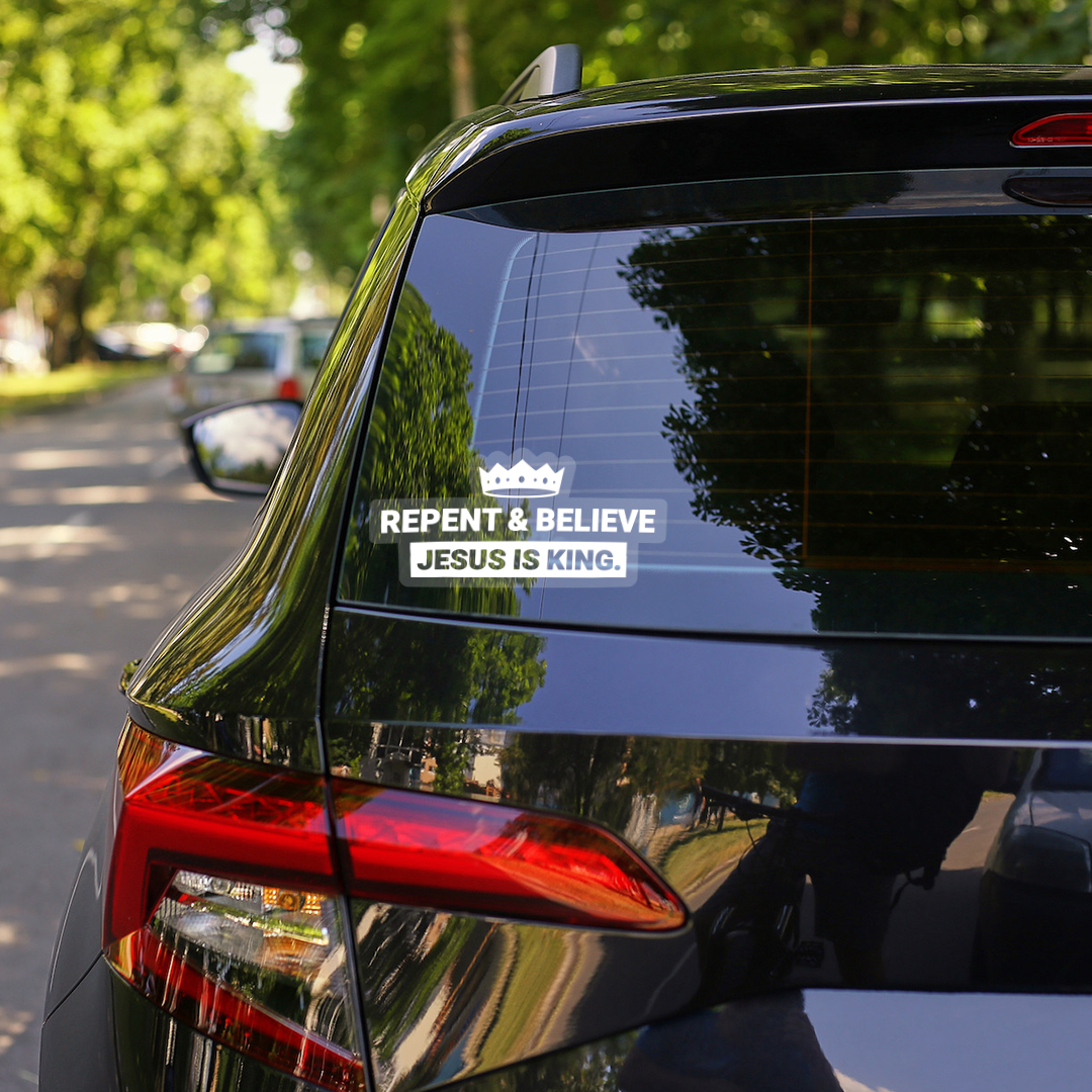Clear vinyl “Repent & Believe – Jesus Is King” decal displayed on a car window, crown-shaped Christian sticker with white bold lettering.